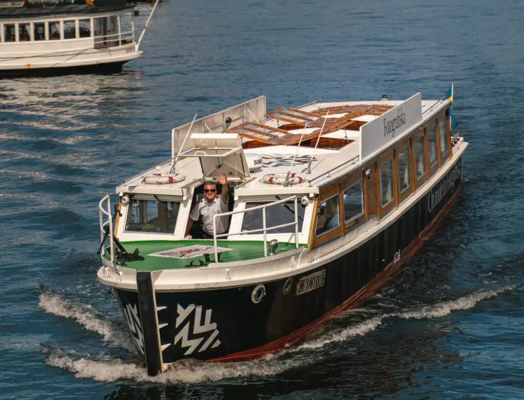 Captain waving from the Sightseeing Ride Fotografiska boat on the water in Stockholm