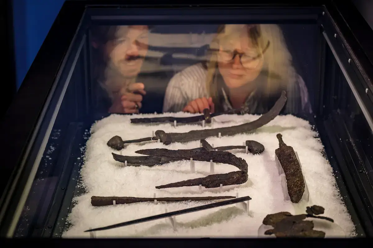 Visitors looking at Viking Age weapons in a display case at the Viking Museum in Stockholm