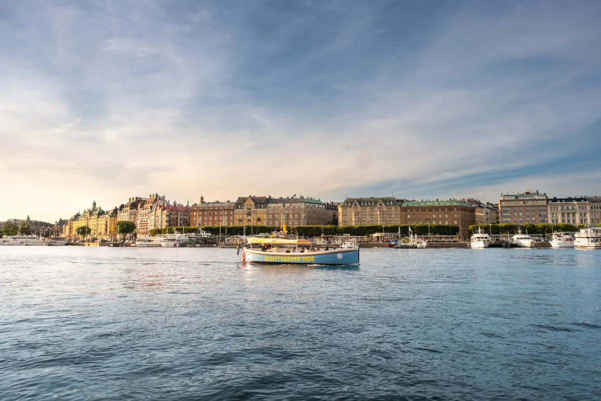 Öppen båt som passerar längs Östermalms strandlinje i Stockholm