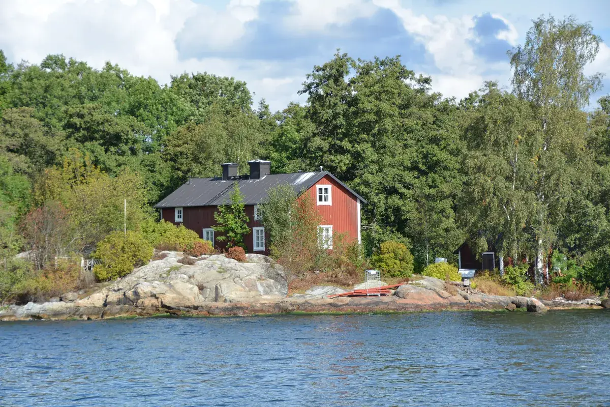 A red wooden house on the rocks by the water on Fjäderholmarna