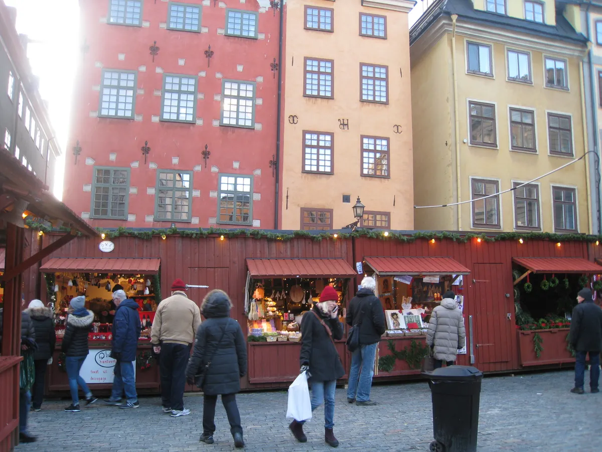 Röda julmarknadsbodar framför de färgglada husen på Stortorget i Gamla stan
