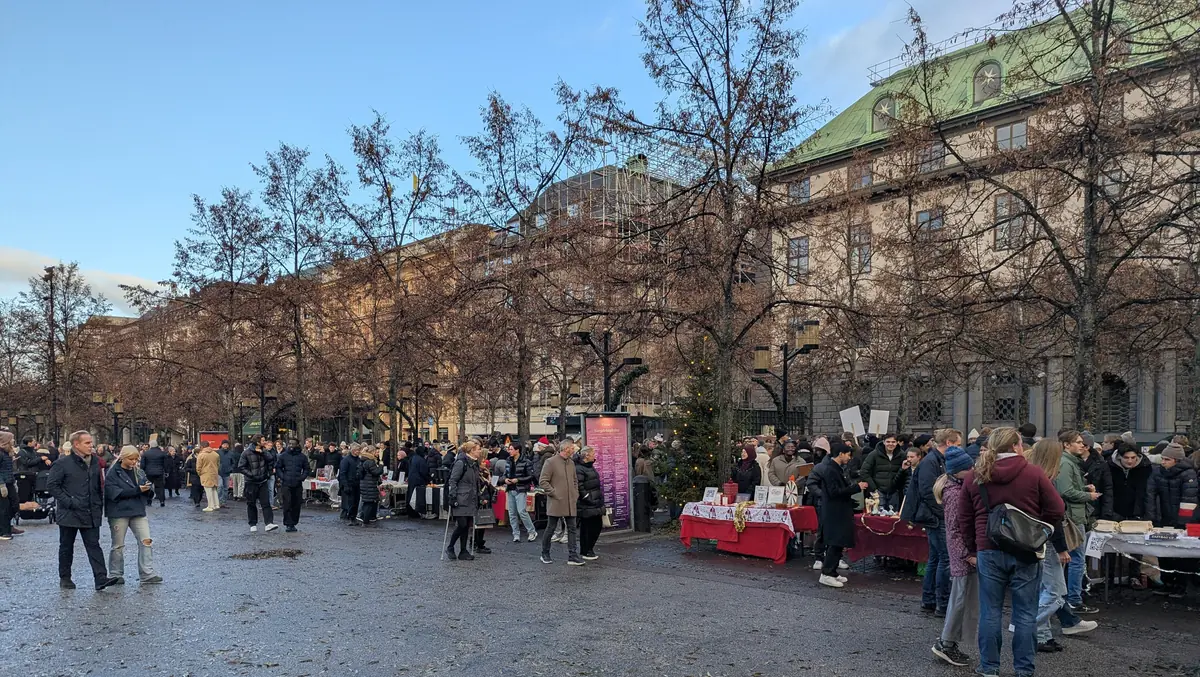 Besökare vid UF-företagens julmarknadsbord i Kungsträdgården med en julgran i bakgrunden