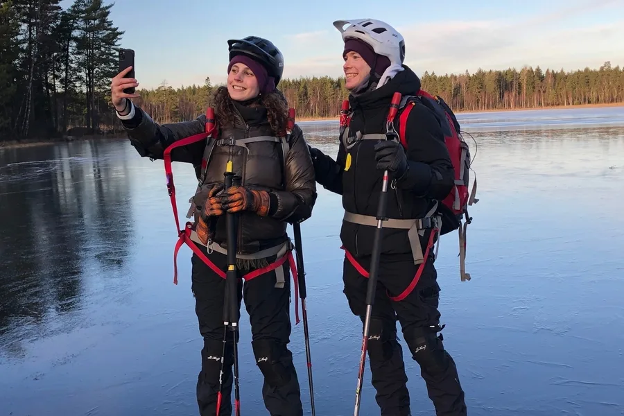 Two skaters with poles and safety gear on natural ice outside Stockholm