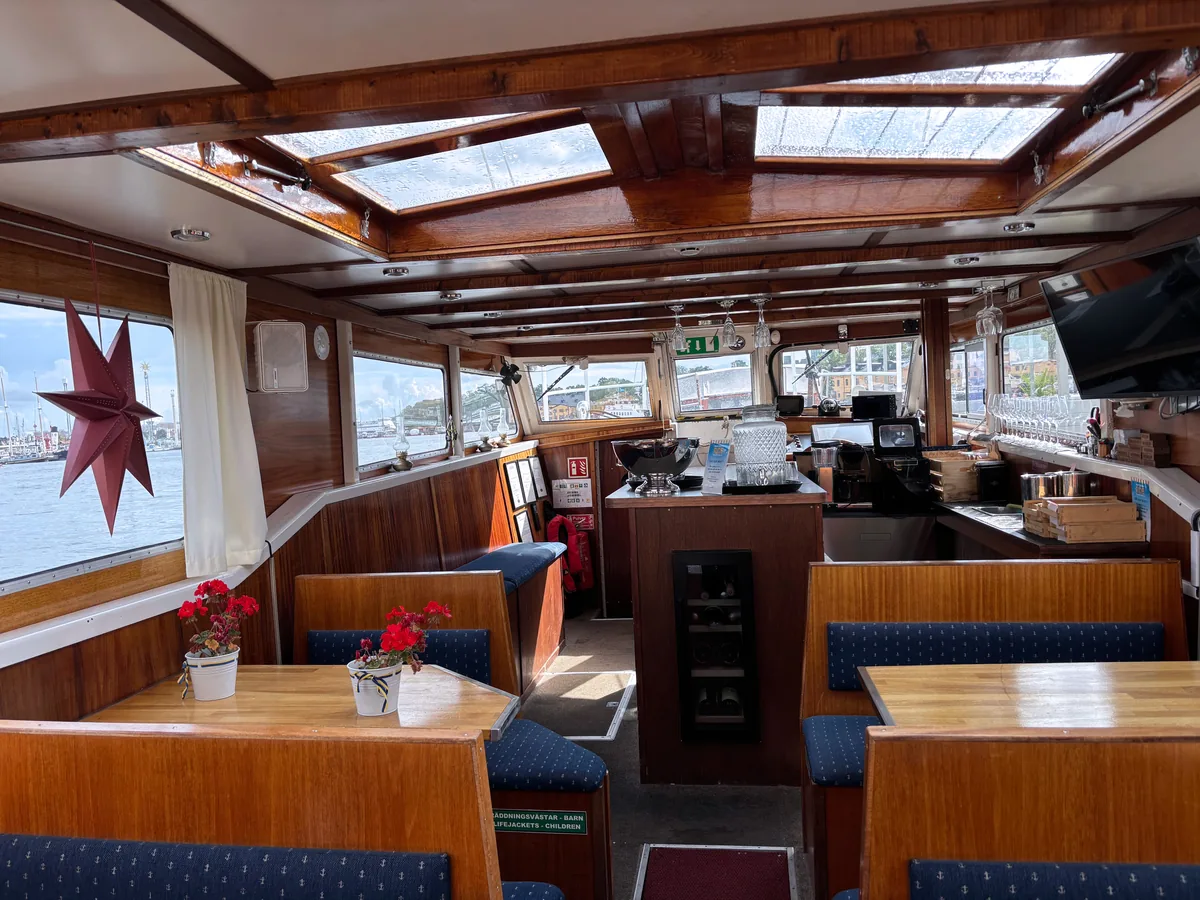The heated wooden cabin on board with blue benches, skylights and Christmas decorations in the windows